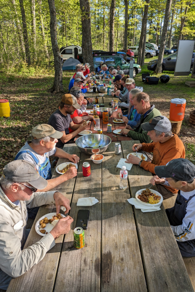 A group of volunteers sit around a picnic table and enjoy a homecooked meal.