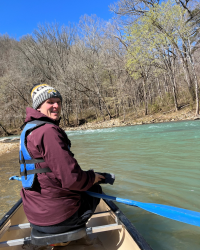 A man smiles while canoeing.