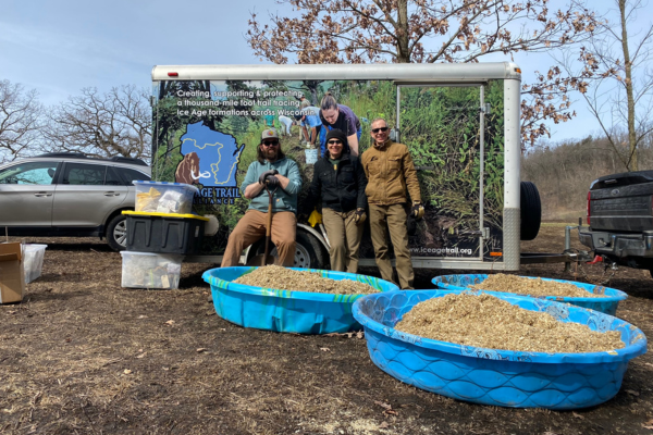 Steve Pence, Land Restoration Specialist, and volunteers pose and smile with native seed they mixed to be spread at the Alliance-owned SwampLovers Preserve in Dane County, Wis. Photo by IATA Staff.
