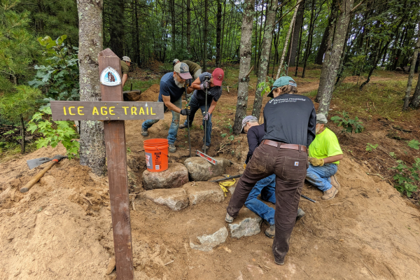 Volunteers build stone staircases next to an Ice Age Trail sign.