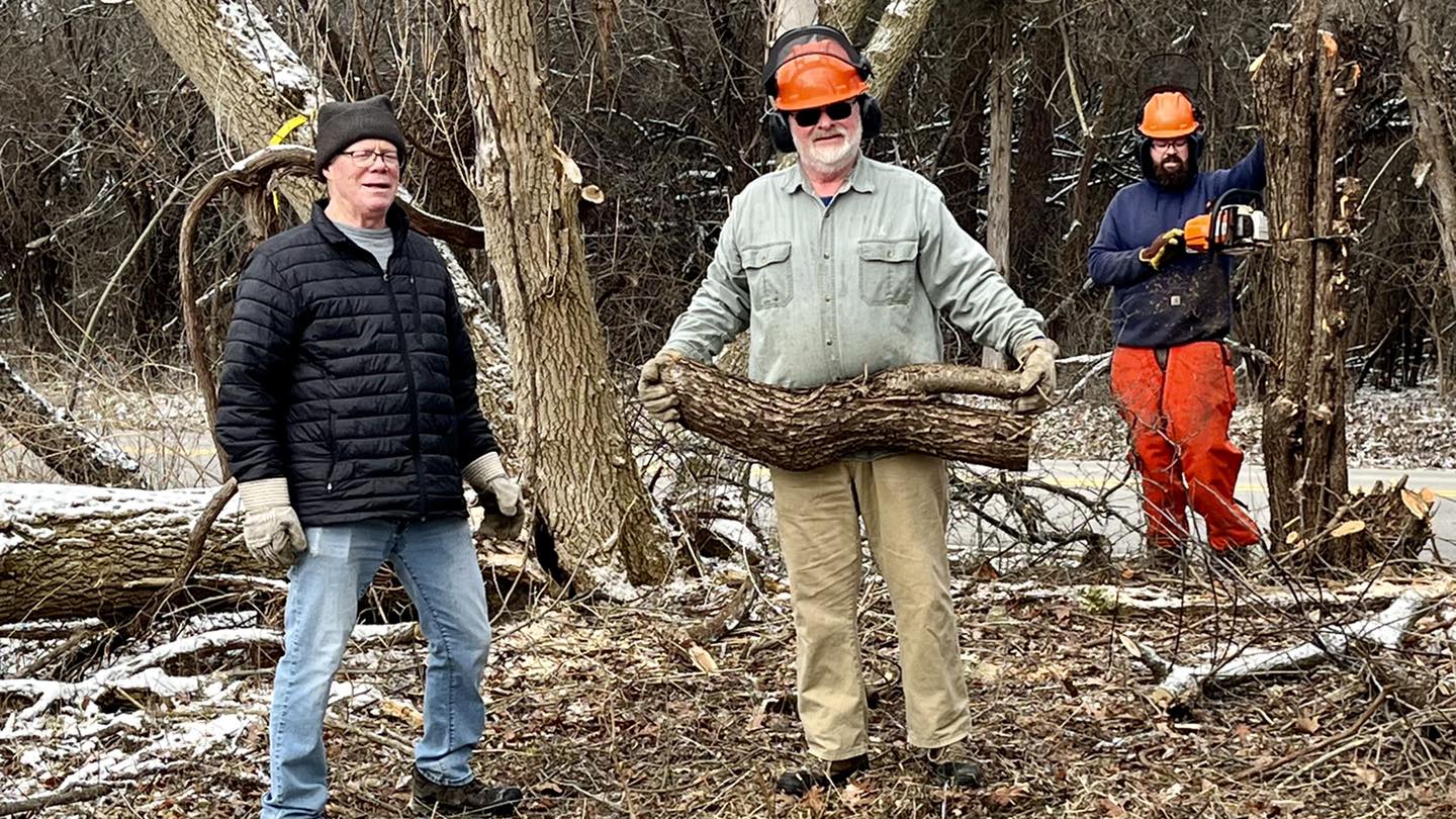 Three volunteers clearing logs and branches from trail