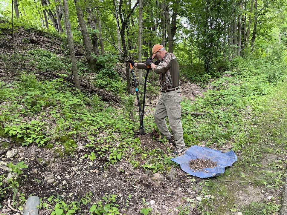 Volunteer digging a hole to install a post on the trail.